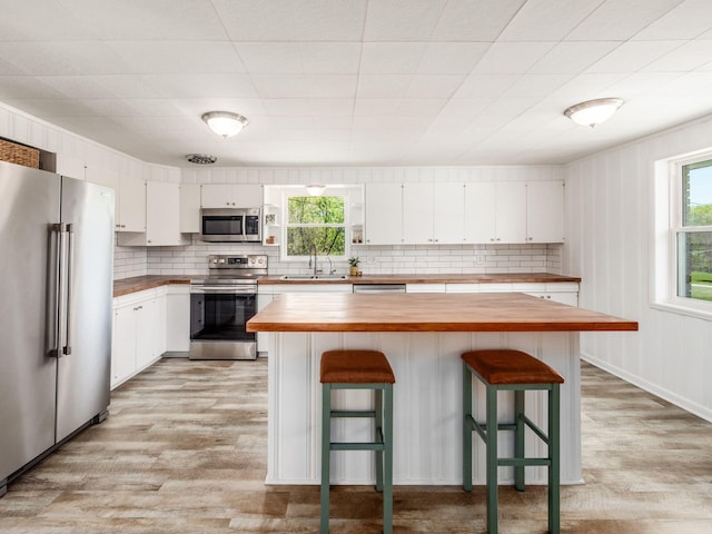 kitchen featuring appliances with stainless steel finishes, wooden counters, a sink, and light wood-style floors