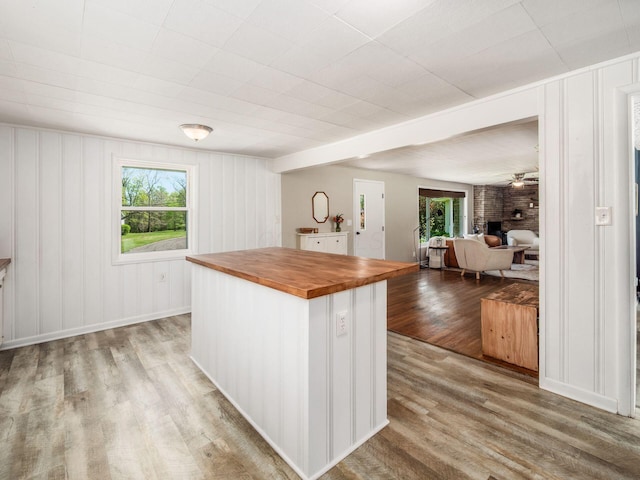 kitchen with a brick fireplace, wood counters, light wood finished floors, and a healthy amount of sunlight