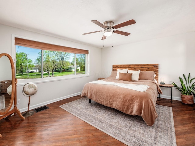 bedroom featuring a ceiling fan, baseboards, visible vents, and wood finished floors