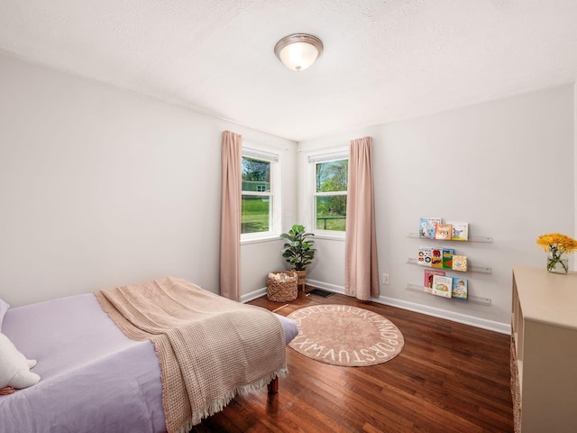 bedroom with baseboards, wood finished floors, and visible vents