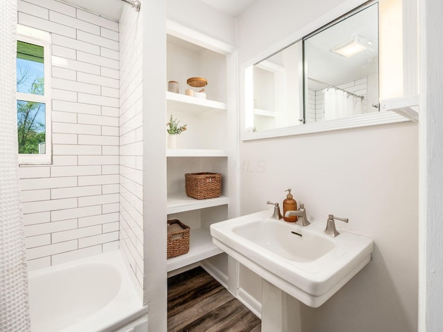 bathroom featuring a sink, wood finished floors, and shower / tub combo with curtain