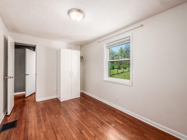 unfurnished bedroom with baseboards, hardwood / wood-style flooring, and visible vents