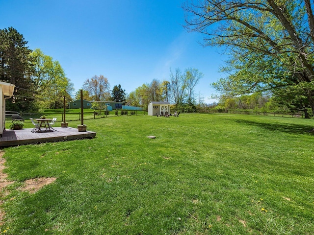 view of yard featuring fence, a wooden deck, an outbuilding, and a shed