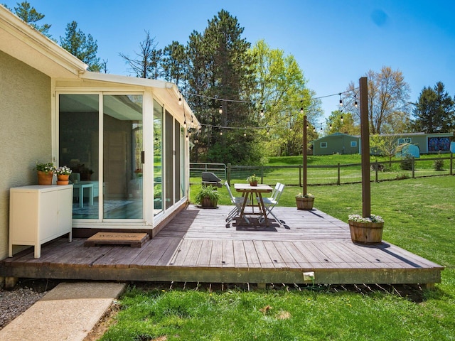 deck with a lawn, fence, and a sunroom