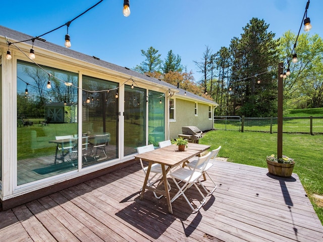 wooden terrace with outdoor dining area, a fenced backyard, a lawn, and area for grilling