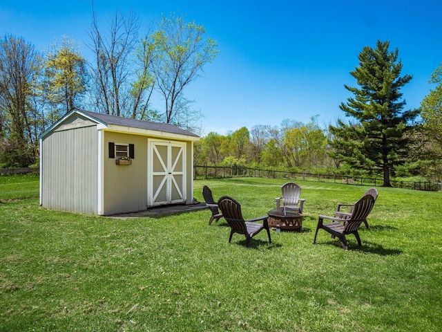view of yard featuring fence, an outbuilding, a shed, and an outdoor fire pit