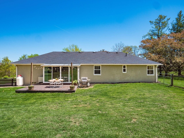back of house with fence, stucco siding, a lawn, and a deck