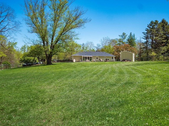view of yard with an outbuilding, a fenced backyard, a detached carport, and a storage unit