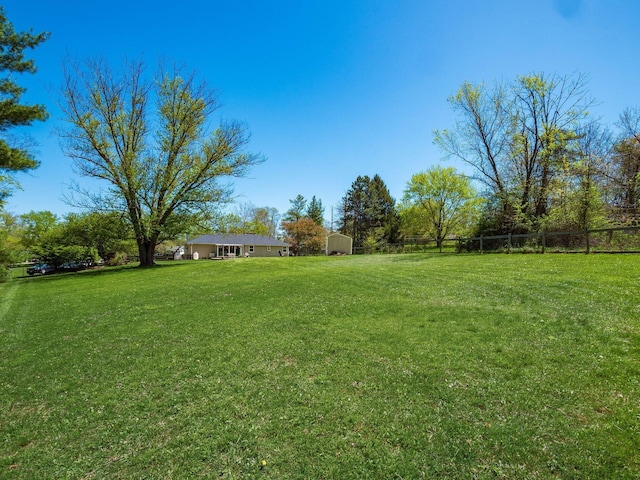 view of yard featuring an outdoor structure, fence, and a storage shed