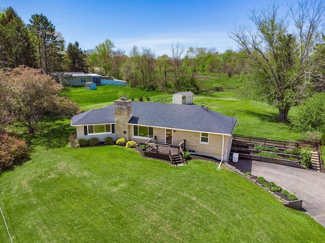 view of front of house featuring a front lawn, a wooden deck, an outbuilding, and a shed