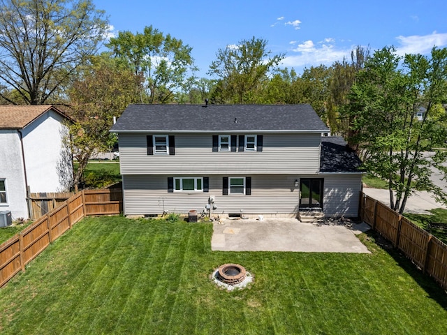 rear view of house with a lawn, a fenced backyard, a fire pit, and a patio
