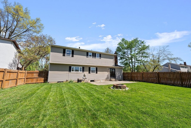 rear view of house with a fenced backyard, a lawn, and an outdoor fire pit