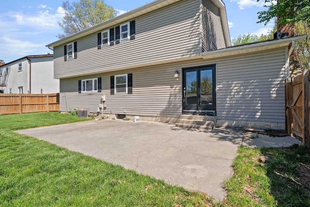 rear view of property featuring fence, central AC unit, a patio area, entry steps, and a lawn