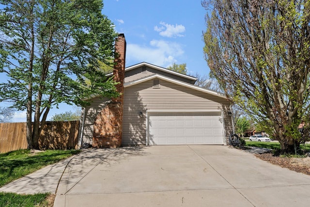 view of side of property with an attached garage, fence, a chimney, and concrete driveway