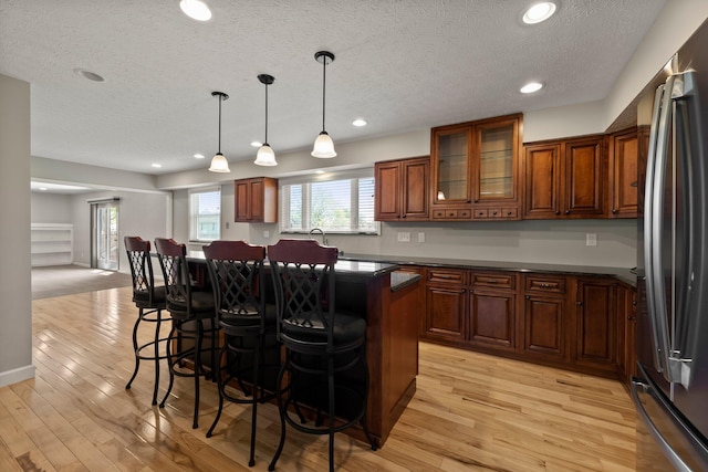 bar with recessed lighting, a textured ceiling, stainless steel refrigerator, and light wood-type flooring