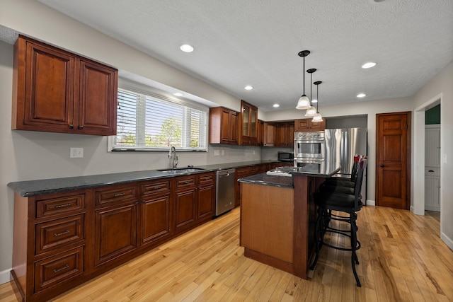 kitchen with a breakfast bar area, appliances with stainless steel finishes, a sink, recessed lighting, and light wood-style flooring