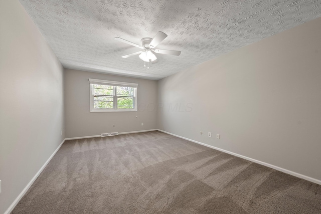 carpeted spare room featuring baseboards, a textured ceiling, ceiling fan, and visible vents
