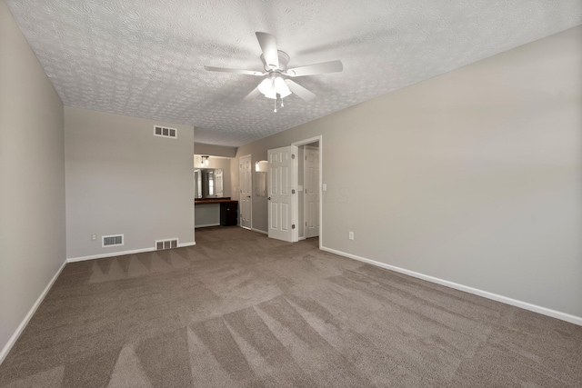 carpeted empty room featuring visible vents, a ceiling fan, and baseboards