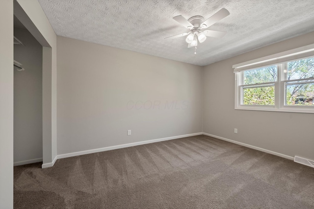 spare room with a ceiling fan, a textured ceiling, visible vents, baseboards, and carpet flooring