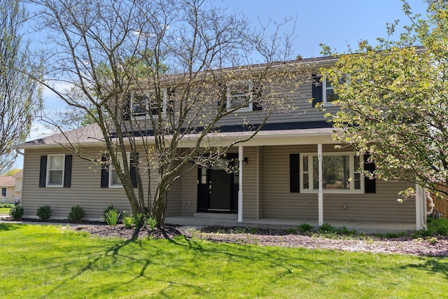 traditional-style house featuring roof with shingles, covered porch, and a front yard
