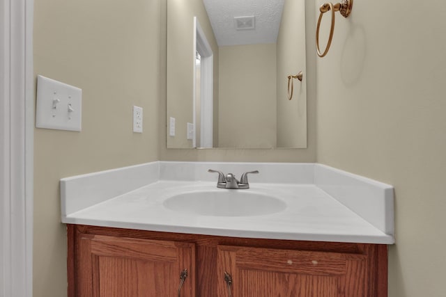 bathroom featuring a textured ceiling, visible vents, and vanity