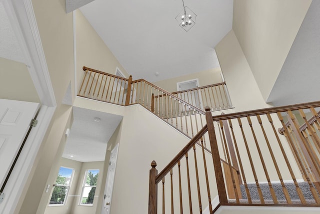 staircase featuring an inviting chandelier and a towering ceiling
