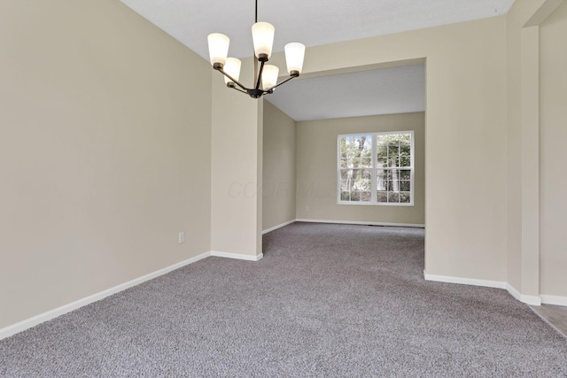 carpeted spare room featuring baseboards and a chandelier