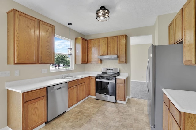kitchen with under cabinet range hood, light countertops, stainless steel appliances, and a sink