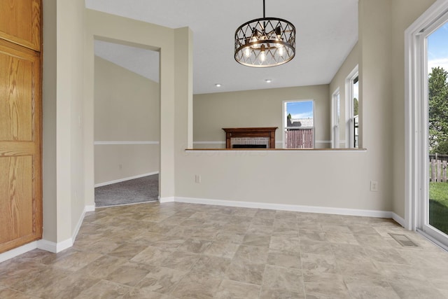 unfurnished living room featuring stone finish floor, baseboards, visible vents, a chandelier, and a tile fireplace