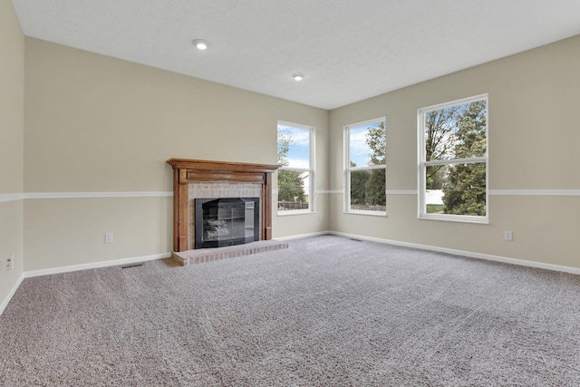 unfurnished living room with a brick fireplace, carpet flooring, baseboards, and a healthy amount of sunlight