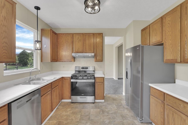 kitchen featuring stainless steel appliances, under cabinet range hood, a sink, brown cabinets, and light countertops
