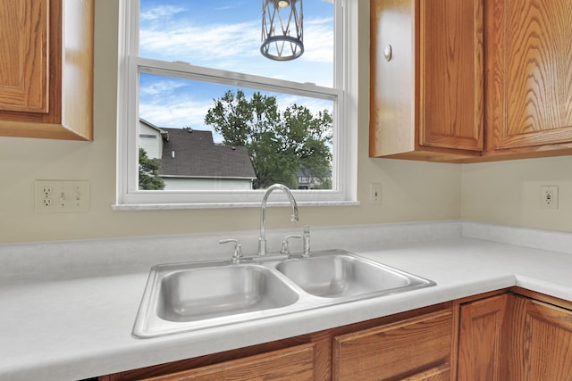 kitchen with a sink, light countertops, plenty of natural light, and brown cabinets