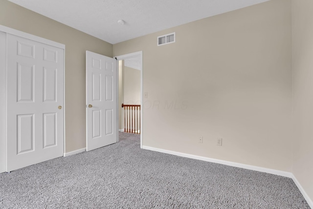 unfurnished bedroom with baseboards, carpet flooring, and visible vents