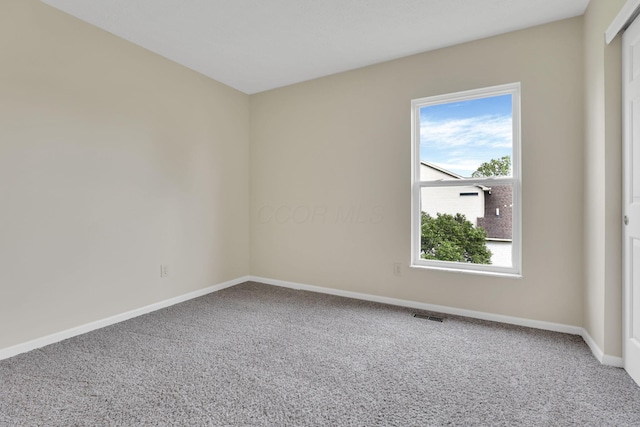 unfurnished room featuring baseboards, carpet flooring, and visible vents