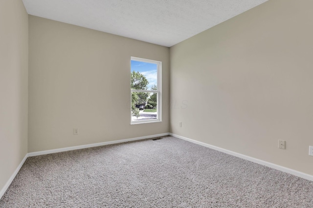carpeted spare room with baseboards, visible vents, and a textured ceiling