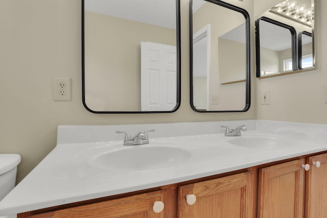 bathroom featuring toilet, double vanity, and a sink