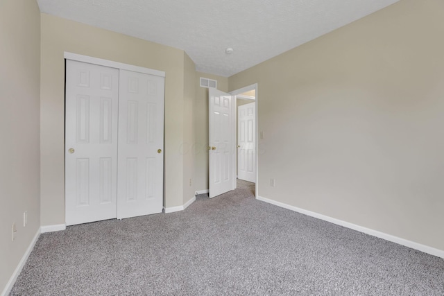 unfurnished bedroom featuring carpet, visible vents, baseboards, and a closet
