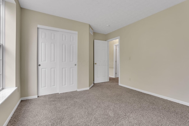 unfurnished bedroom featuring baseboards, a closet, visible vents, and carpet floors