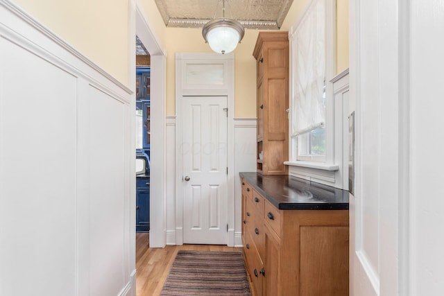 doorway featuring a decorative wall, wainscoting, and light wood finished floors