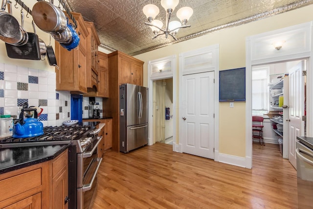 kitchen with brown cabinetry, dark countertops, an ornate ceiling, a chandelier, and stainless steel appliances