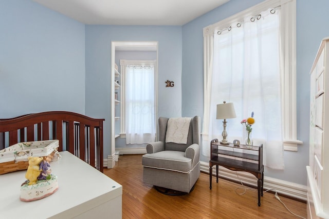 bedroom featuring light wood-type flooring, a crib, and baseboards