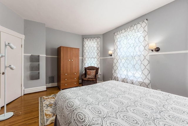 bedroom featuring baseboards, visible vents, and wood finished floors