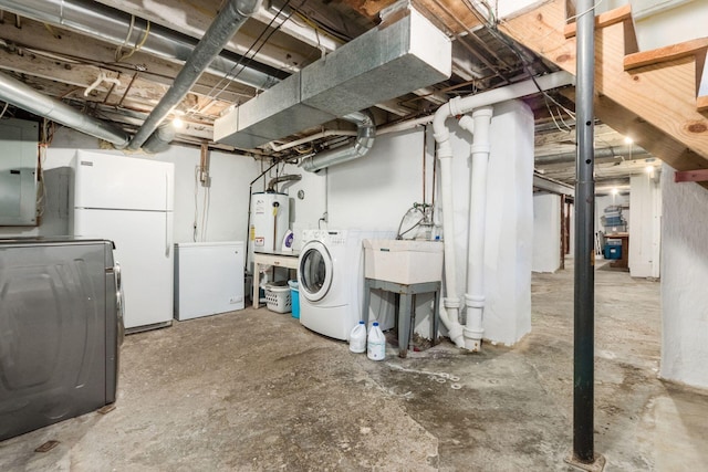 unfinished below grade area featuring freestanding refrigerator, water heater, fridge, and washing machine and clothes dryer