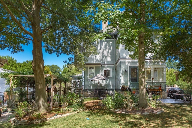 exterior space featuring a lawn, a patio, fence, and a chimney