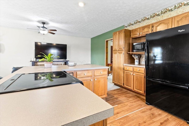 kitchen with ceiling fan, a textured ceiling, light countertops, black appliances, and light wood-style flooring