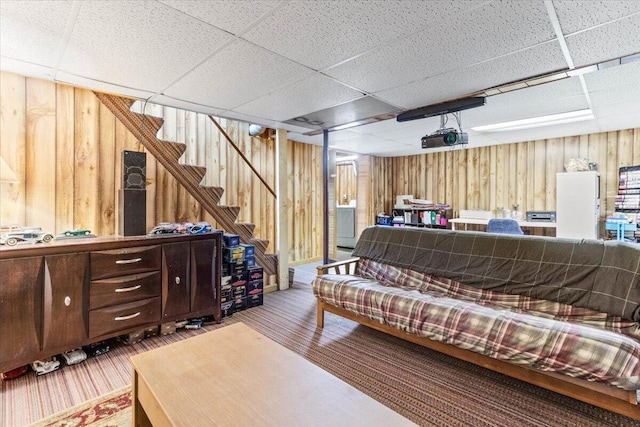 living room featuring wood walls and a paneled ceiling