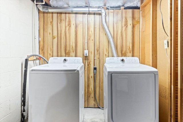 washroom with concrete block wall, laundry area, and washing machine and dryer