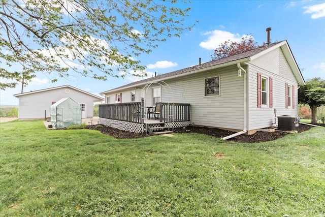 rear view of property featuring a lawn, a deck, and cooling unit