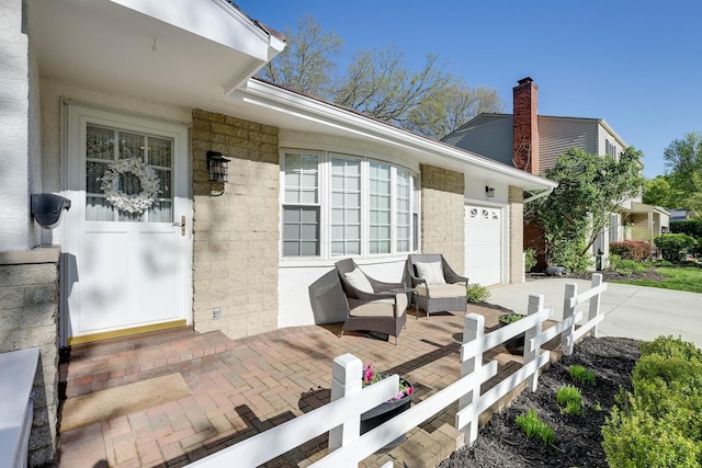 entrance to property featuring an attached garage, a chimney, and concrete driveway