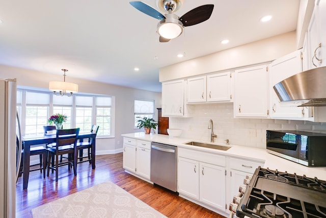 kitchen featuring white cabinets, appliances with stainless steel finishes, a sink, backsplash, and under cabinet range hood